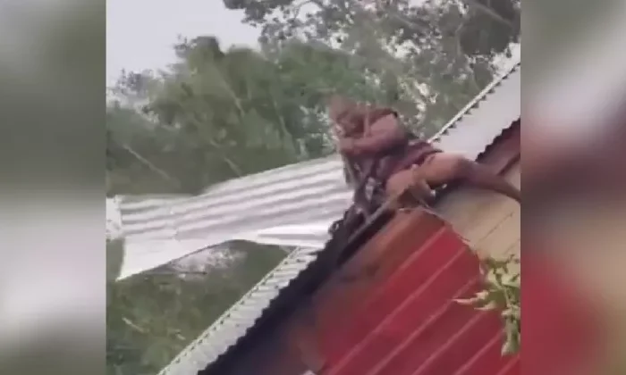 Captan a mujer sujetando el techo de su casa para evitar que Beryl lo destruya